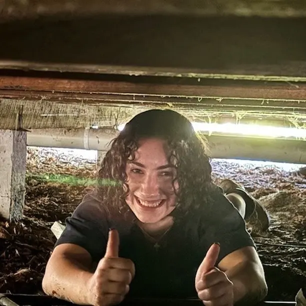 Person giving thumbs up in a crawlspace.